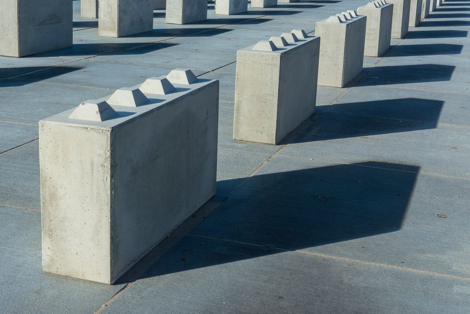 Pracownicy układający betonowe bloczki typu LEGO na budowie wiaty